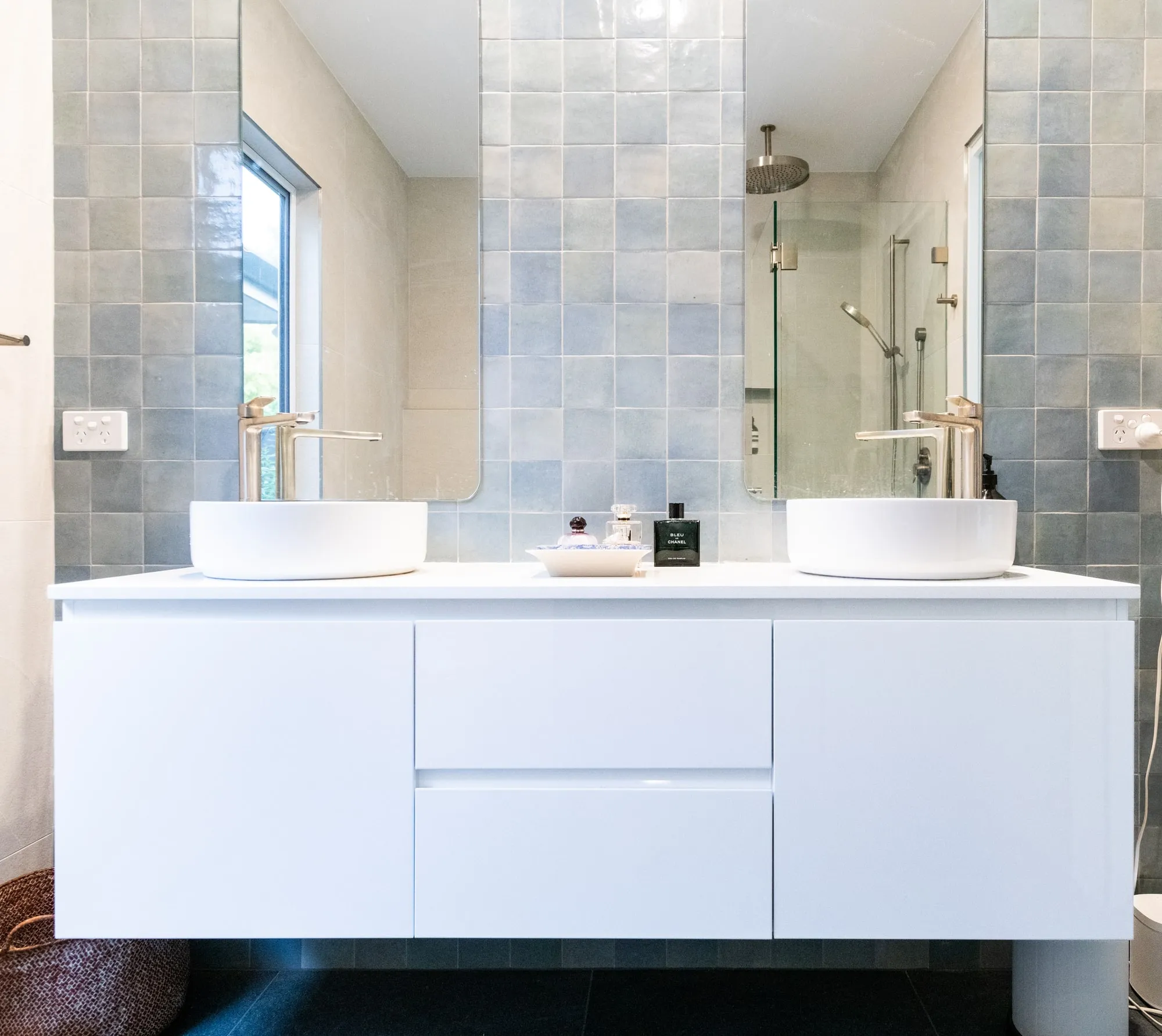 Ensuite with a double vanity, two round basins and blue wall tiles