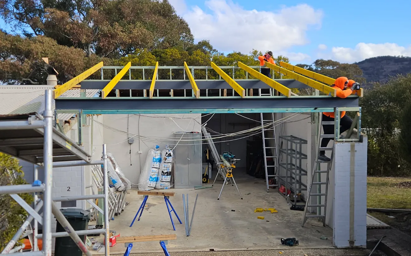 Builders installing new roof rafters over garage