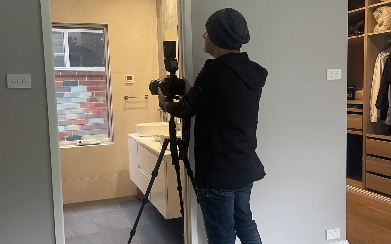 Paul standing in a door with is camera and tripod taking images of an ensuite