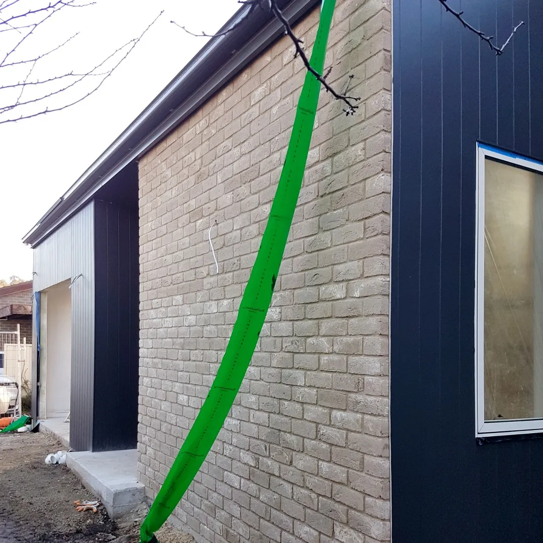 Pale brick feature wall meeting dark vertical cladding on the new extension