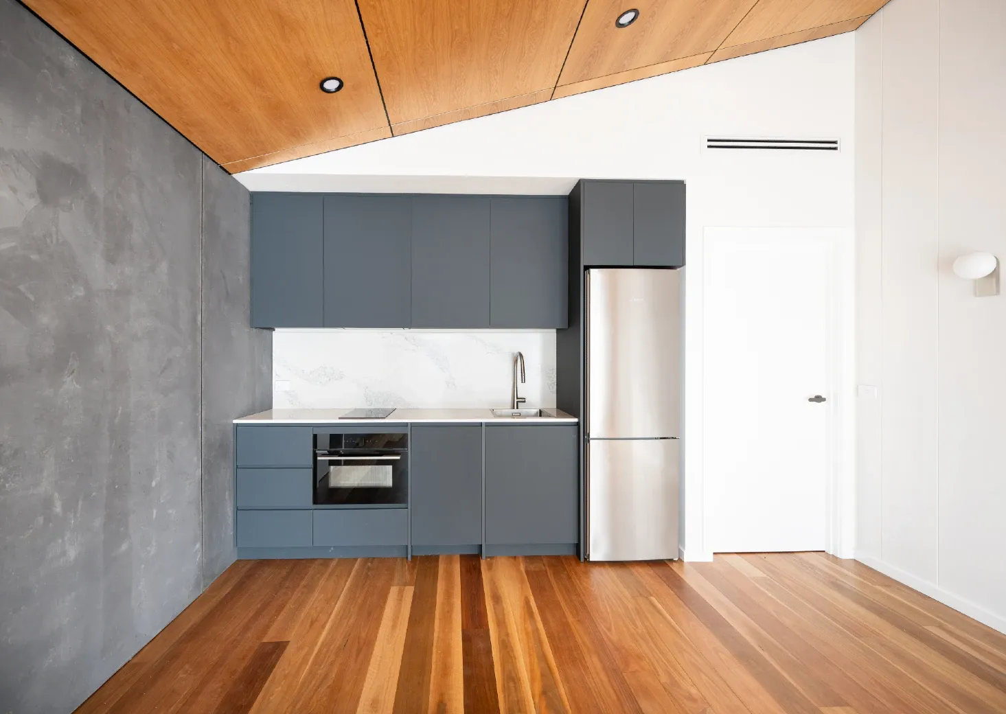 Simple dark grey kitchenette, rustic grey feature wall and raked ceiling