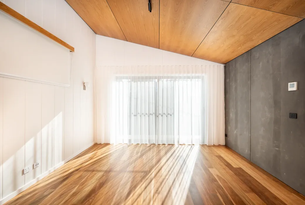 Sun streaming into a living room featuring hardwood floors and a raked ceiling