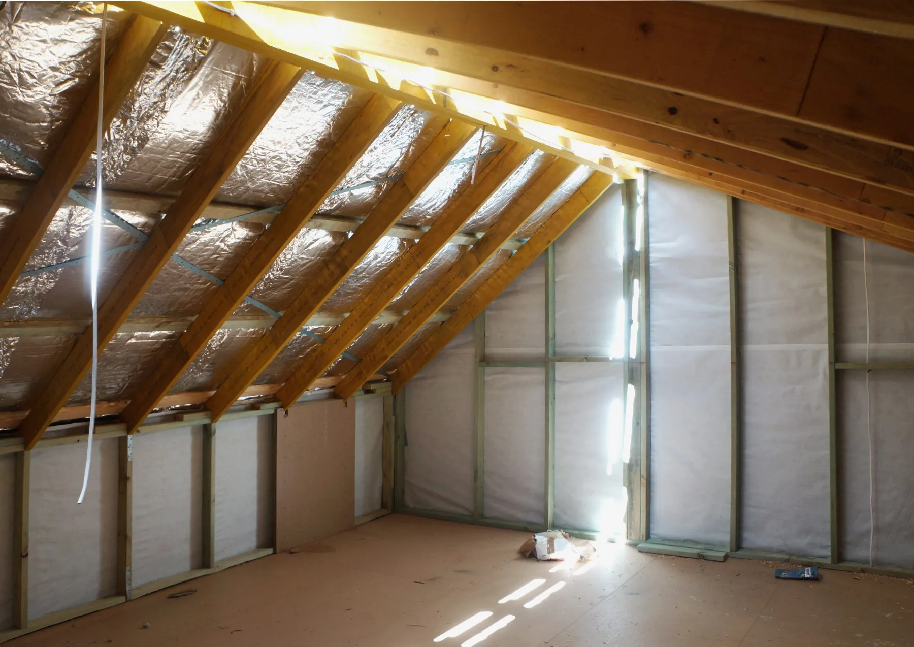 Attic space under the roof trusses with foil insulation, before lining