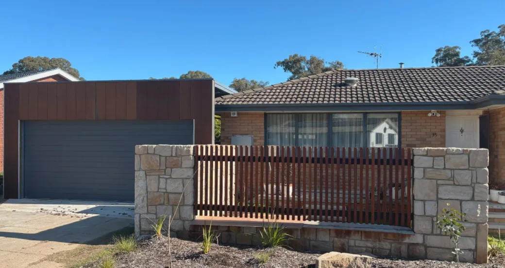 Front of house showing newly completed timber carport and sandstone courtyard wall.