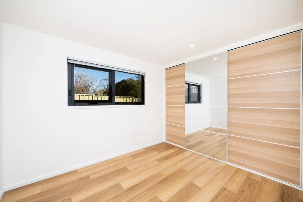 Bedroom showing build in storage with timber look door and highlight window