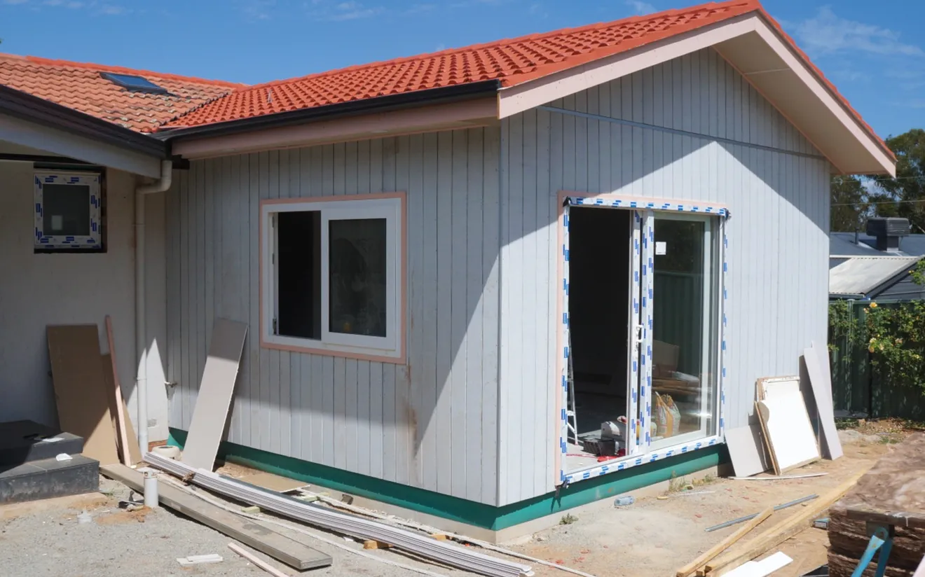 Construction site with roof and cladding installed on a small addition