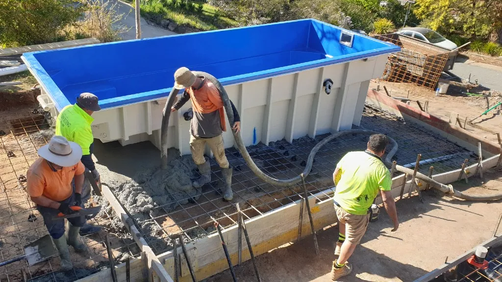 4 men pouring concrete around a small pool